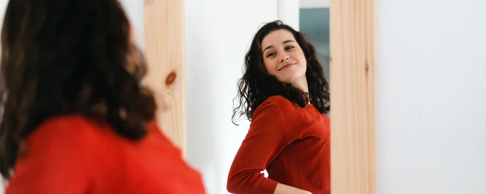 žena s úsmevom sa obzerá v zrkadle
